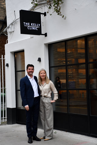 Two people standing in front of a building with 'The Kelly Clinic' sign.